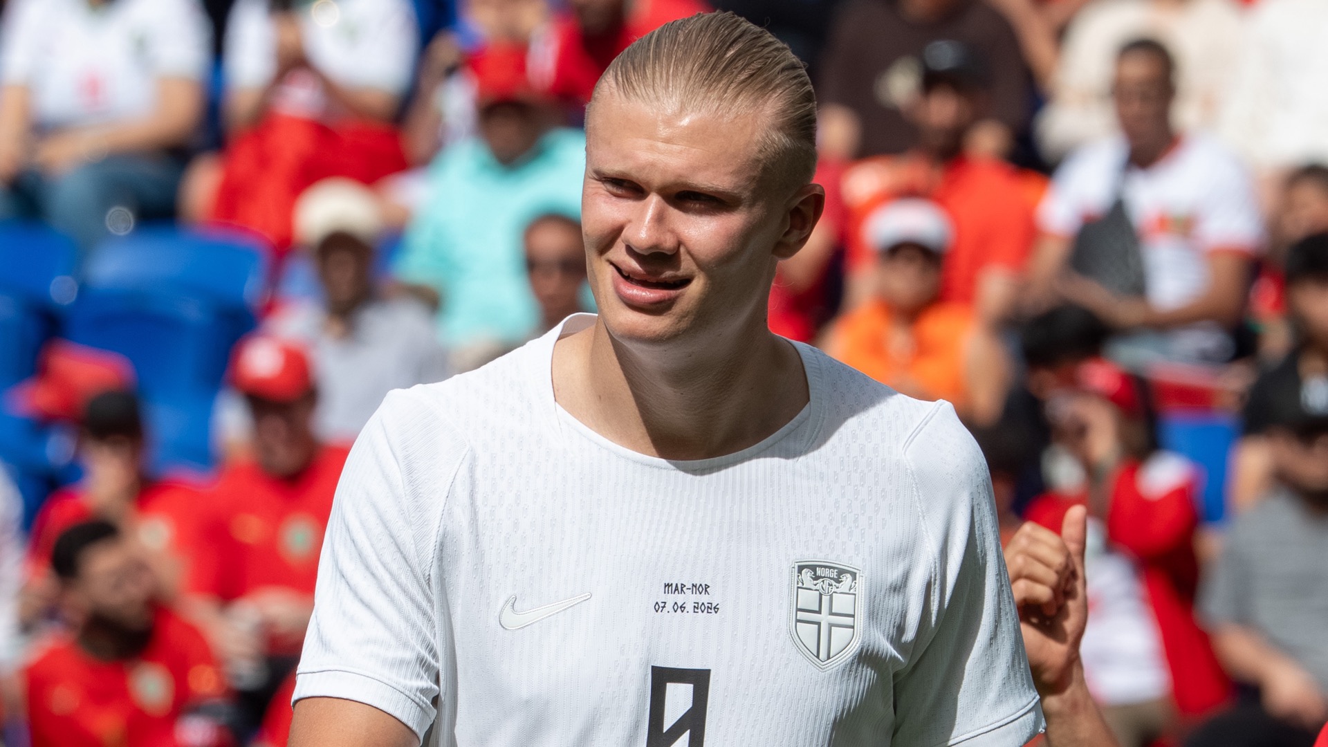 Erling Haaland in Norway's white number 9 kit, smiling and relaxed during the Morocco vs Norway match in June 2026, with a blurred crowd behind him